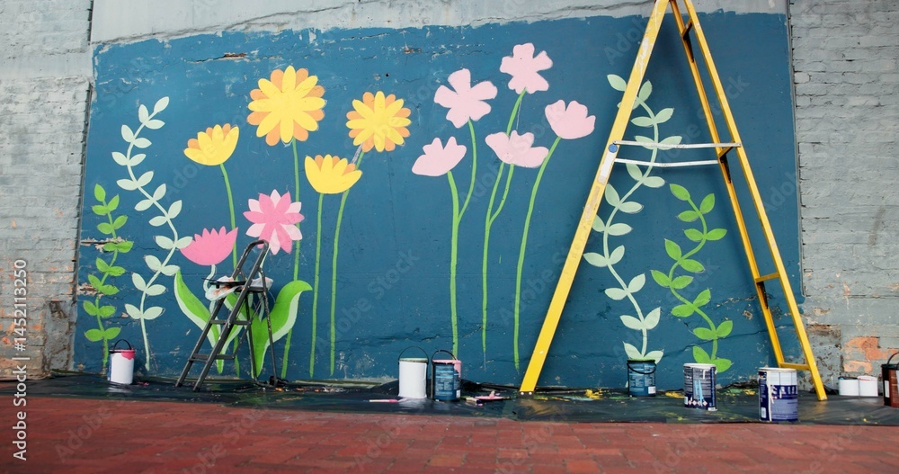 Fototapeta premium Creative, ladder and painting with mural on wall on street for decoration, improvement or renovation. Background, DIY and flowers outdoor for community art project, design or neighborhood upliftment
