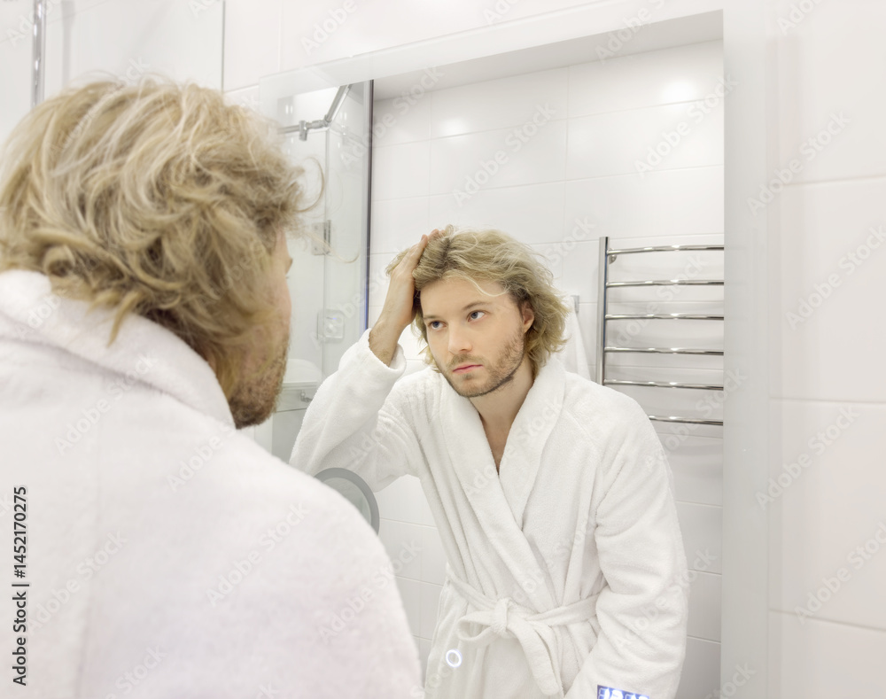 morning routine, young man looking in mirror in bathroom morning routine, young man looking in mirror in bathroom