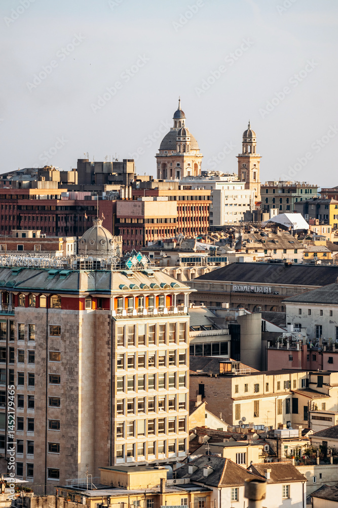 Fototapeta premium View of Genoa's rooftops at sunset, showcasing the city’s historic skyline and warm golden light.