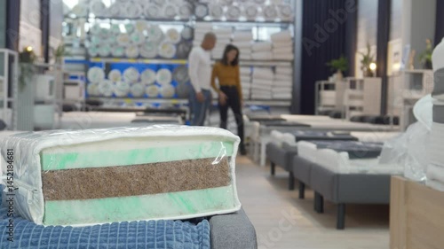 Couple exploring orthopedic mattress options in a cozy furniture store