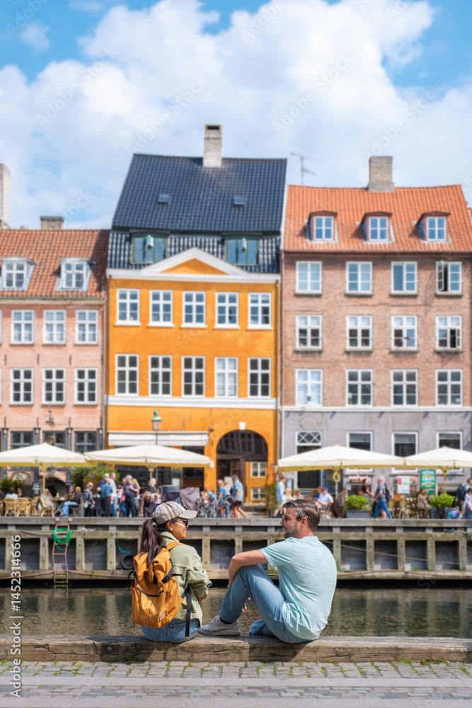 Obraz premium Charming waterfront view in Copenhaen with a couple enjoying sunny day by the canal