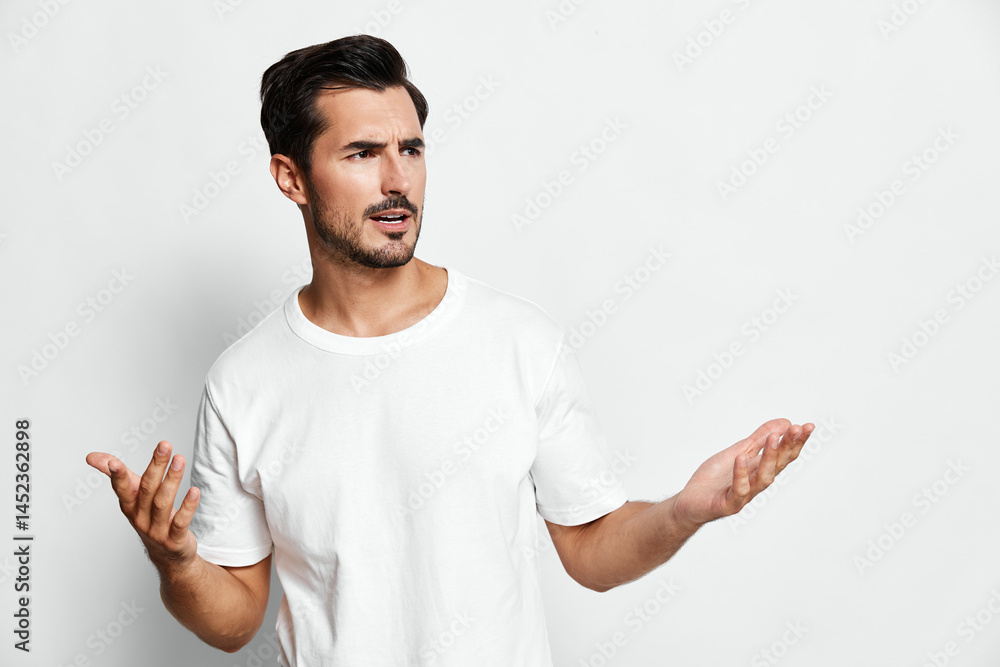 Confused man with stylish short hair wearing a plain white t-shirt, looking at the camera with a questioning expression, isolated on a soft gray background. Confused man with stylish short hair wearing a plain white t-shirt, looking at the camera with a questioning expression, isolated on a soft gray background.