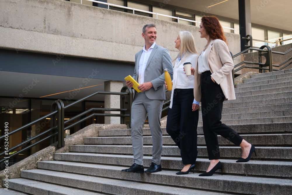 Businesspeople walking down the stairs of their office building after a meeting, talking about work