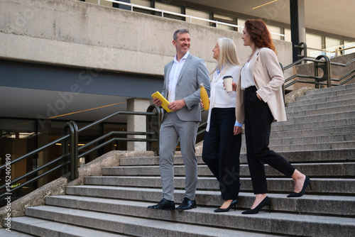 Obraz na płótnie Businesspeople walking down the stairs of their office building after a meeting, talking about work w salonie