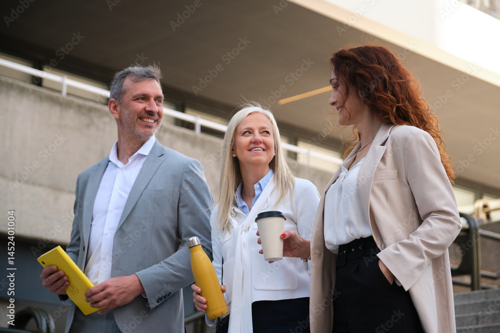Businesspeople walking and talking during coffee break outside office