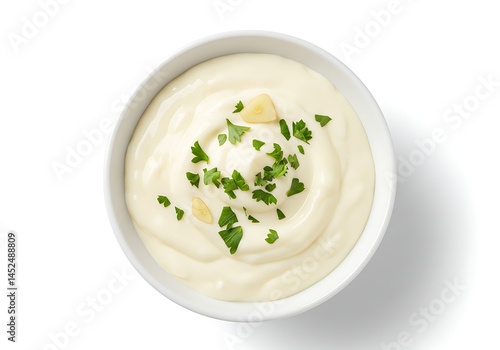 A top view of a white bowl filled with creamy sauce and garnished with fresh green parsley herbs