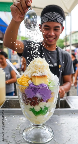 Colorful halo-halo dessert in a clear glass: shaved ice, ube, beans, leche flan, and evaporated milk. Street vendor assembling with crushed ice flying