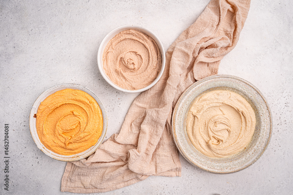 Various hummus dips in different colours. Hummus with dry crackers, top view. Vegan and traditional hummus as healthy and vegan snack.