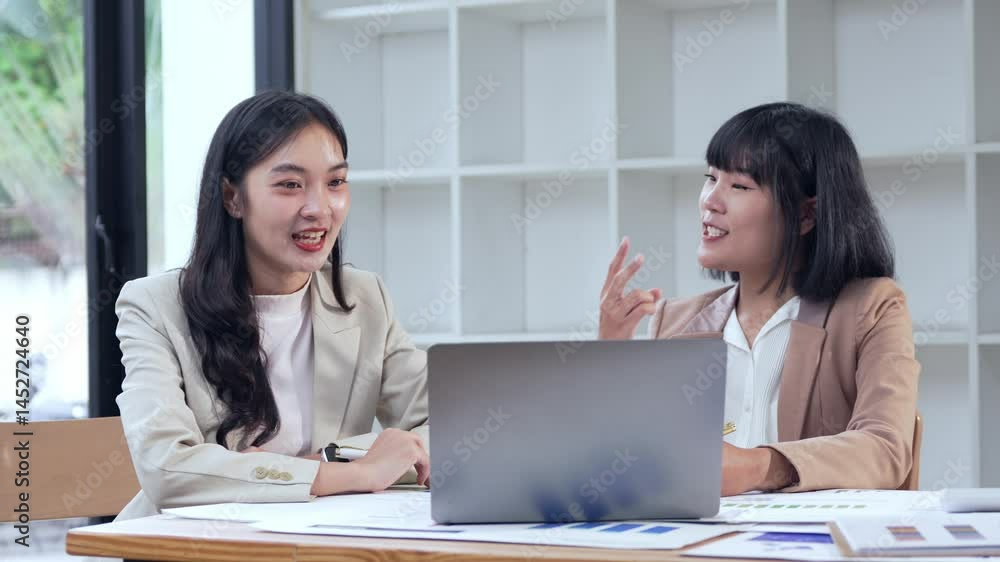 Professional Asian businesswomen collaborating during strategic marketing meeting, analyzing data and sharing innovative solutions in modern corporate workspace Professional Asian businesswomen collaborating during strategic marketing meeting, analyzing data and sharing innovative solutions in modern corporate workspace