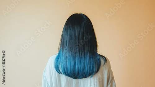 Asian female with blue ombre hair rear view against neutral background