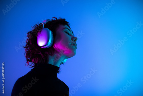young beauty woman in headphones listening music in neon blue purple light