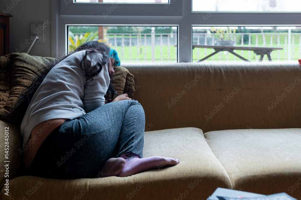 Depressed woman sitting on sofa at home, feeling sad and lonely