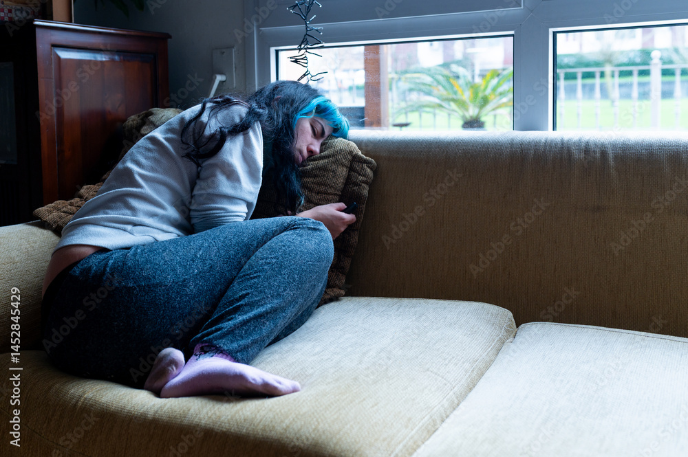 Sad woman suffering from depression, lying on the sofa at home