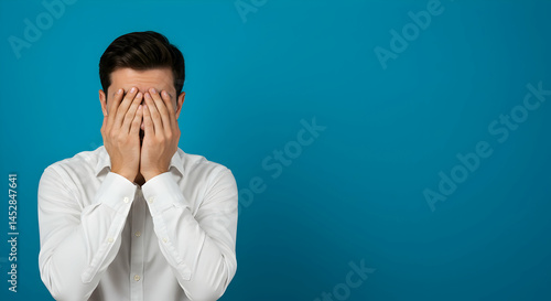 Obraz na płótnie Man with Hands Over Face Expressing Frustration Against Blue Background w salonie
