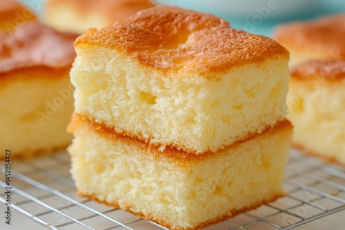 Two stacked golden brown sponge cake squares on a wire rack, light and airy texture