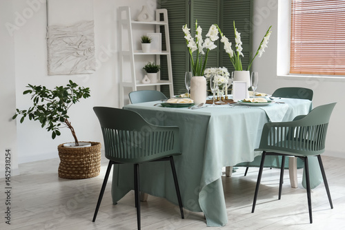Interior of light room with served dining table and white Gladiolus flowers