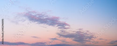 A beautiful blue sky with a few clouds and a pinkish hue. sky is calm and peaceful, and the clouds add a sense of depth and texture to the scene