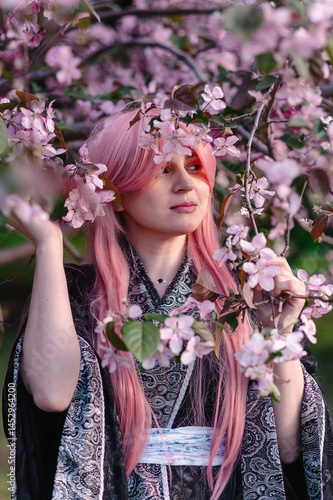 Girl in anime kimono next to pink apple tree
