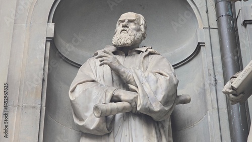 Florence, Italy - 3 January 2025. Marble statue of Galileo Galilei by Aristodemo Costoli, showing his contemplative gaze and hands holding a telescope, part of the Uffizi’s exterior sculpture series.