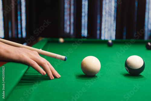 Female Player Aims Cue Toward Billiard Balls
