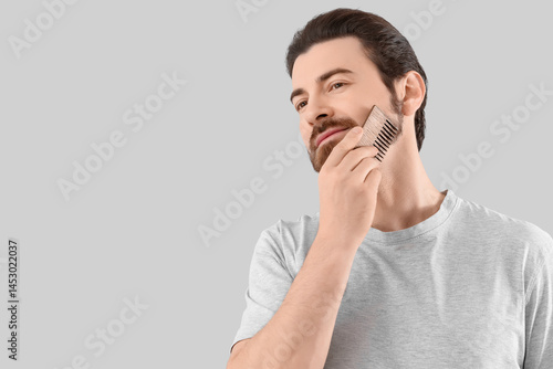 Handsome young man combing ...