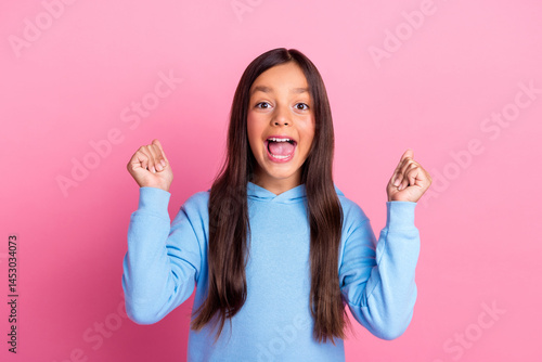 Obraz na płótnie Excited preteen girl in blue sweatshirt making happy gestures against a vibrant pink background w salonie