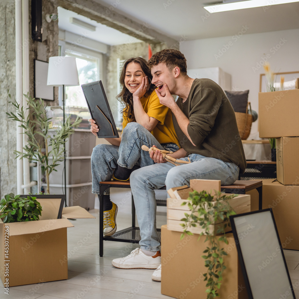 Fototapeta premium Happy adult couple having fun while unpacking boxes together