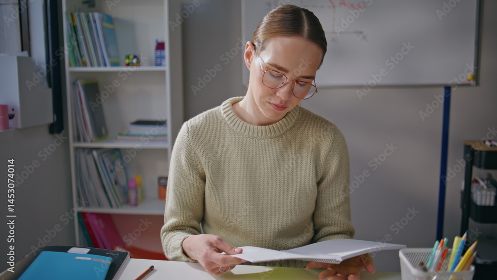 Serious woman checking homework class room closeup. Tired educator taking break