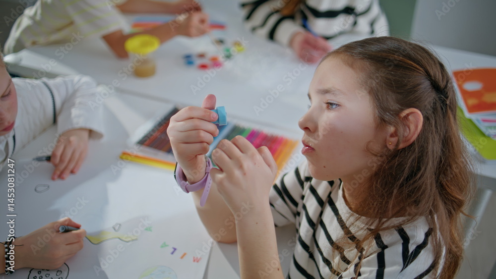 Funny girl holding stamp creating art in school class room closeup. Kid drawing