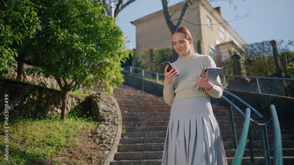 School teacher going staircase with smartphone at spring city. Woman calling