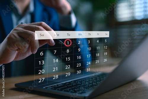 Obraz na plátne Businessman scheduling a digital calendar on laptop, highlighting the first of the month, symbolizing time management, appointment booking, event planning, productivity, and smart scheduling system