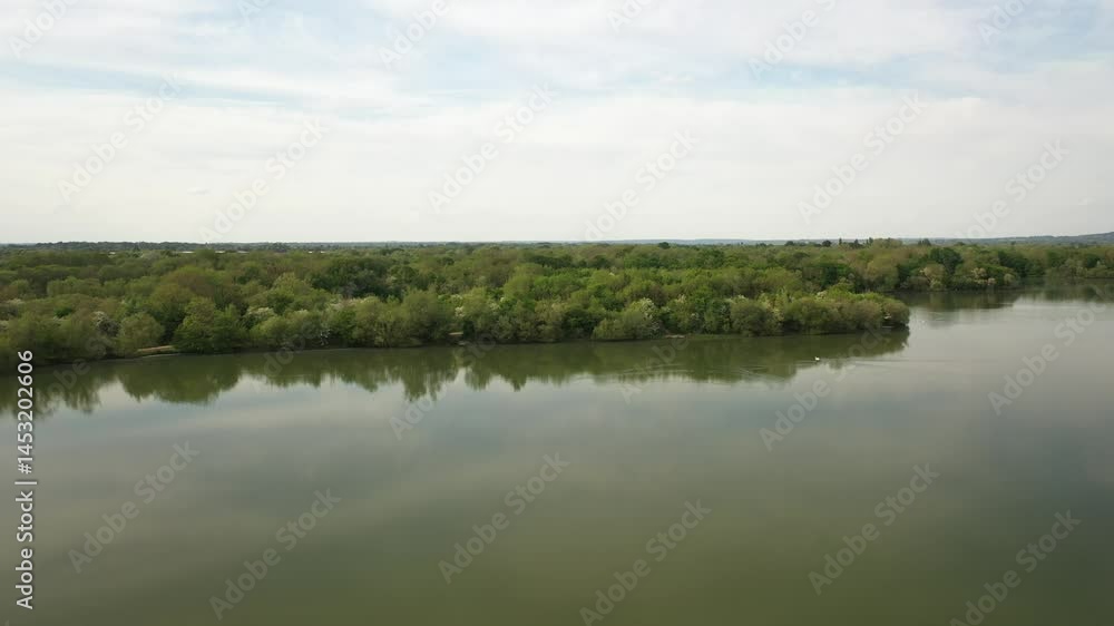 This video features a tranquil lake with dense, lush green trees lining its banks.