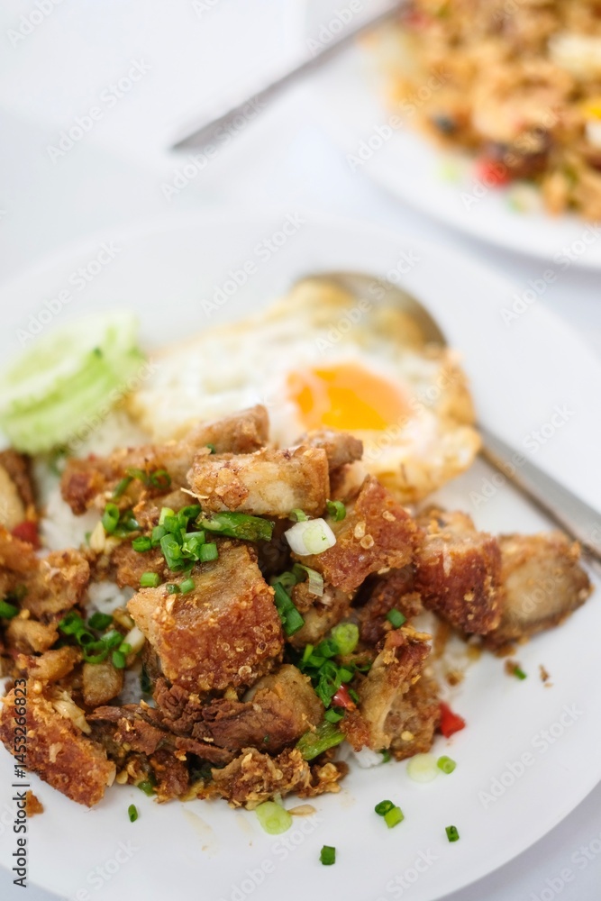 A plate of crispy pork belly stir fry with holy basil (kra pao moo grob), white rice and a fried egg at a street food stall at Soi 20 - Silom, Bangkok, Thailand A plate of crispy pork belly stir fry with holy basil (kra pao moo grob), white rice and a fried egg at a street food stall at Soi 20 - Silom, Bangkok, Thailand