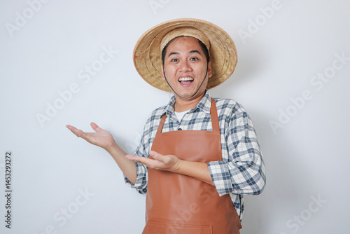 Adult Asian man wearing farmer hat showing happy face expression while his hand presenting something