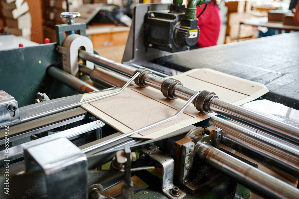 Fototapeta premium Efficient machine folding cardboard flaps in a bustling packaging facility during a productive daytime operation