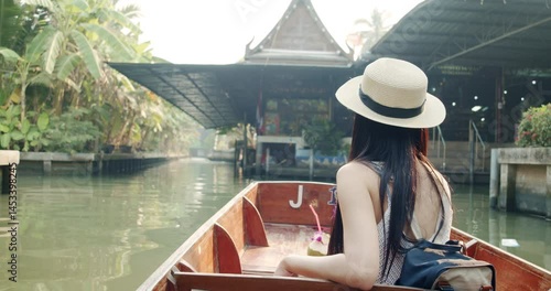 Young Asian tourist woman cheerful and happy to eat street food and sight seeing travel by boat along the canel at Damnoen Saduak Floating Market Thailand