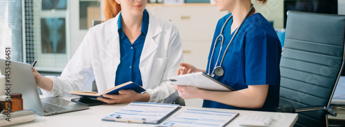 Doctor and nurse team using tablet to review medical results. Diverse healthcare professionals in modern hospital clinic