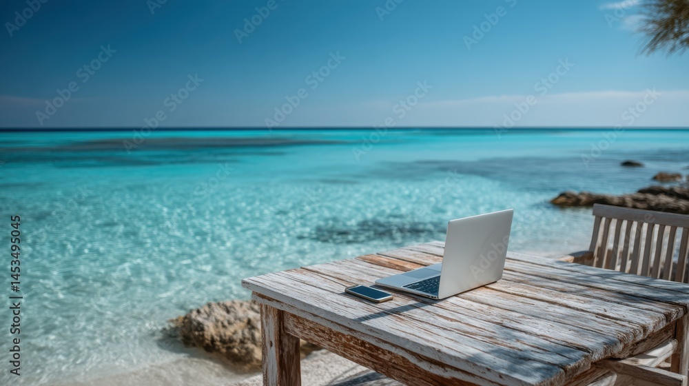 Obraz premium laptop and smartphone on weathered driftwood table facing turquoise sea