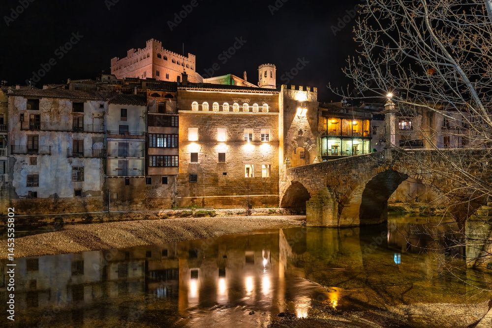 Houses illuminated at night next to the river that passes next to the town of Valderrobles, Teruel, Matarrana.