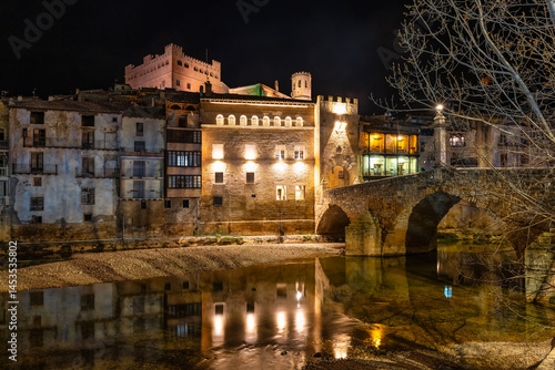 Obraz na płótnie Houses illuminated at night next to the river that passes next to the town of Valderrobles, Teruel, Matarrana. w salonie