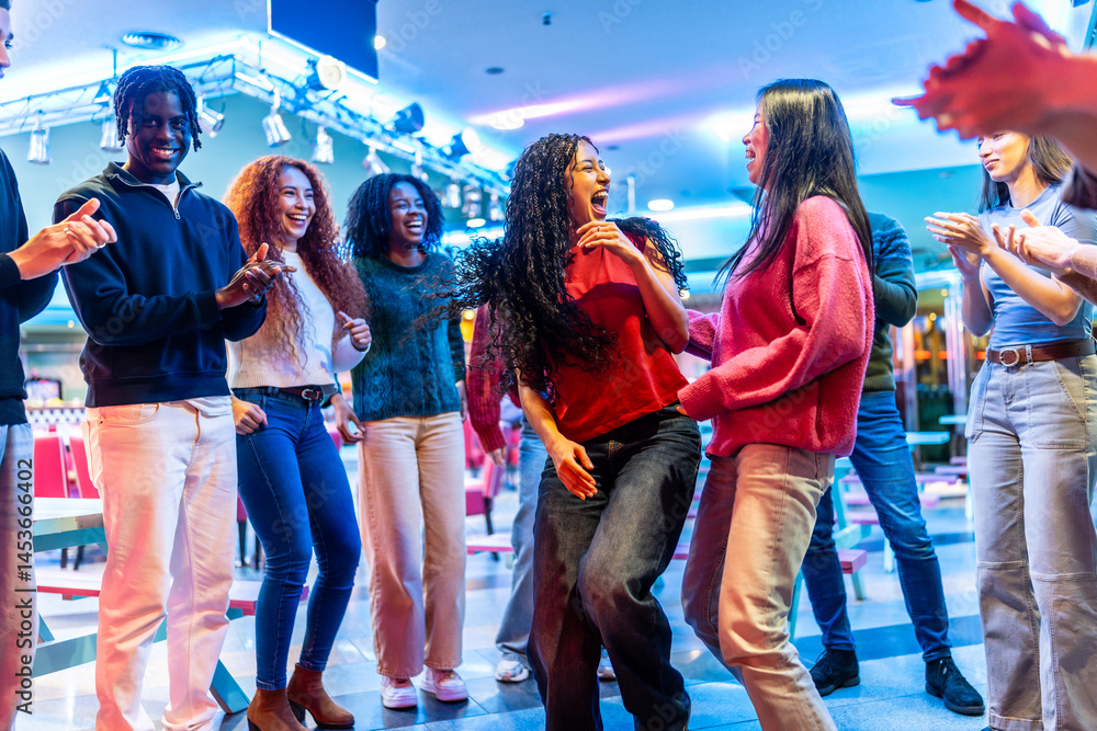 Happy multiethnic friends dancing and enjoying time together at bowling alley