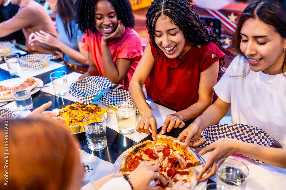 Happy multi ethnic friends sharing pizza and nachos at bowling alley