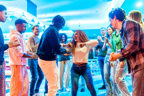 Happy multiethnic friends dancing together in bowling alley