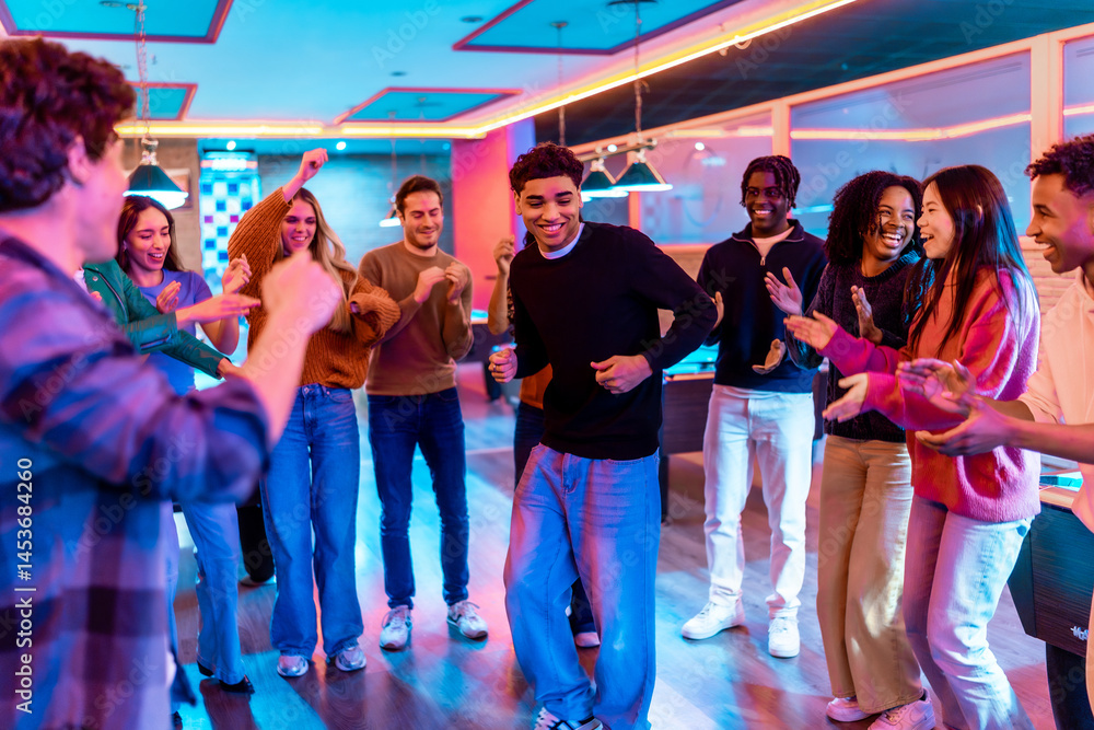 Multiethnic friends enjoying weekend dancing and games at bowling alley