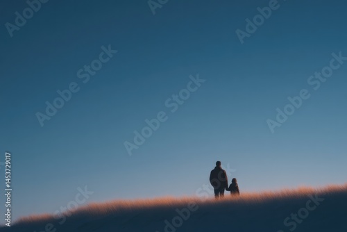 father and child holding hands silhouetted against clear blue sky