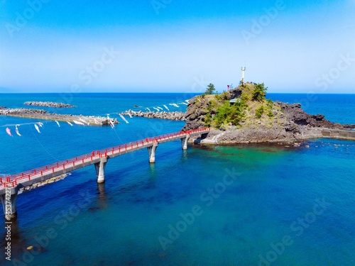 糸魚川市能生の弁天岩と青い海、空に舞う鯉のぼり｜5月の空撮風景