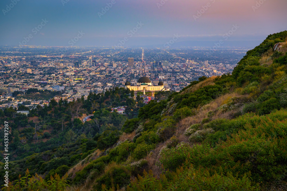 Obraz premium Sunset view of the lit-up Griffith Observatory with Hollywood and the Los Angeles cityscape in the background.