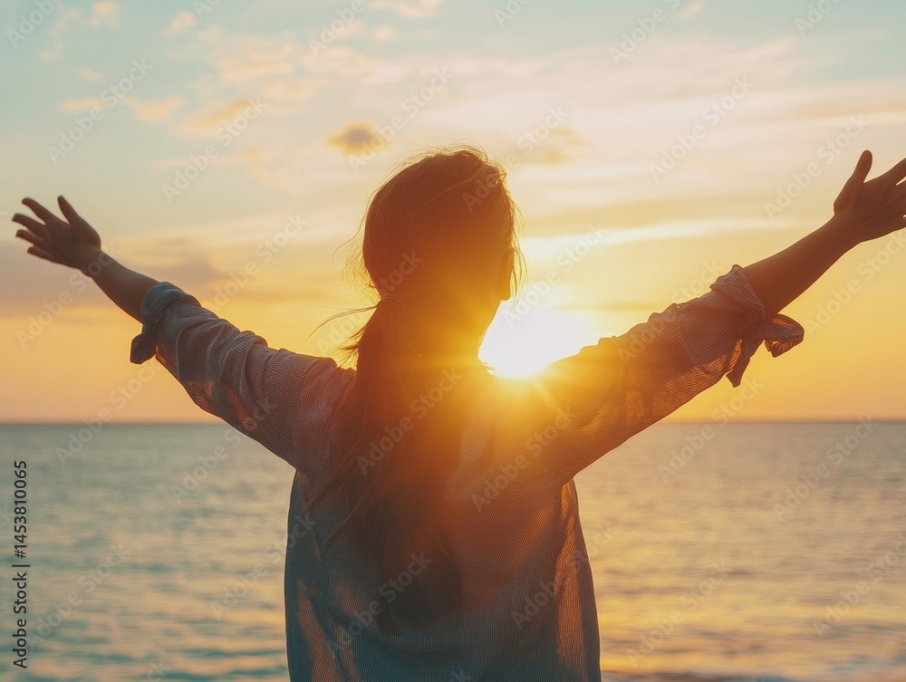 Woman embracing the beauty of a sunset at the beach with arms outstretched for a feeling of freedom and tranquility.