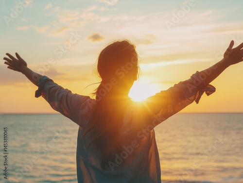 Obraz na płótnie Woman embracing the beauty of a sunset at the beach with arms outstretched for a feeling of freedom and tranquility. w salonie