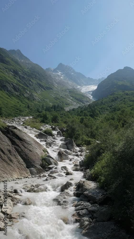 Mountain river flowing through a green valley with glaciers in the distance under clear blue sky offering beautiful nature scene. Mountain river flowing through a green valley with glaciers in the distance under clear blue sky offering beautiful nature scene.